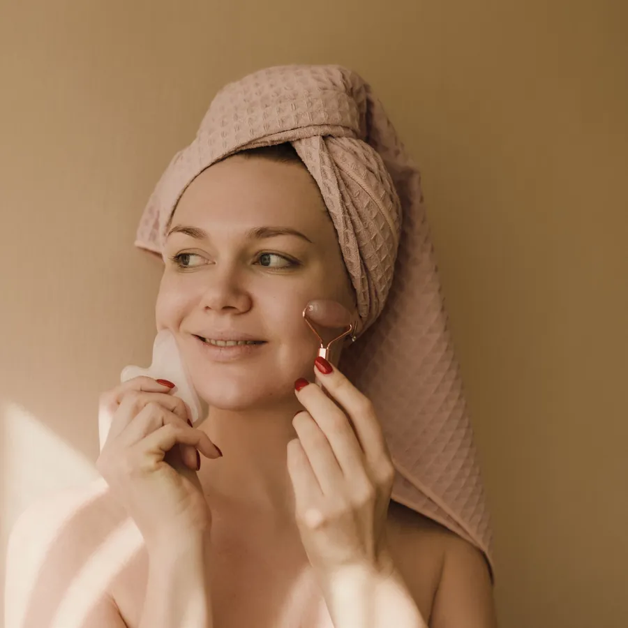 Femme en serviette qui passe un rouleau de massage sur son visage